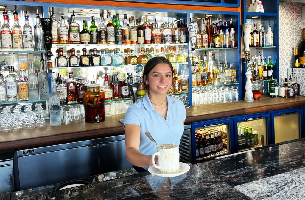 Waitress serving cup of clam chowder at the bar