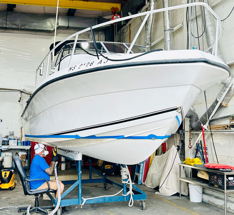 Guy paining boat bottom prep