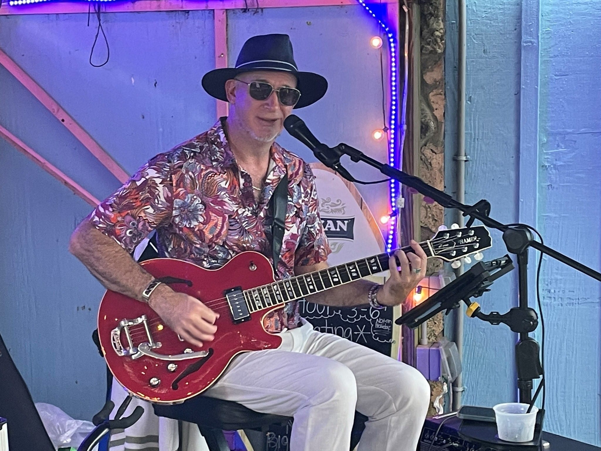 Guy with flowered shirt hat, playing guitar