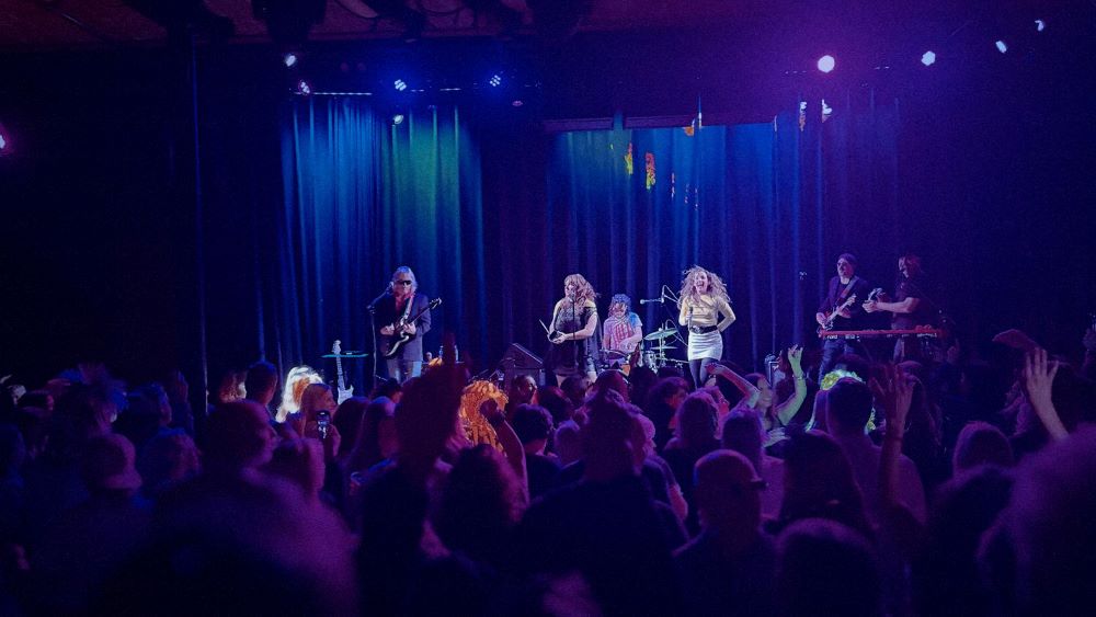 a live band on stage concert curtains and back of peoples heads