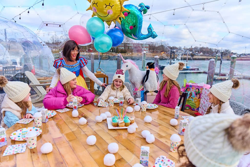 girls with hats on and snow white in a clear igloo dome