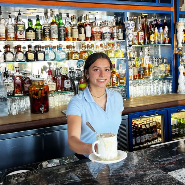 Waitress serving cup of clam chowder at the bar