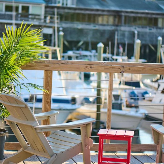chair on a deck with a red table overlooking boats