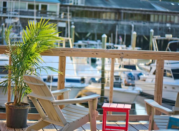 chair on a deck with a red table overlooking boats