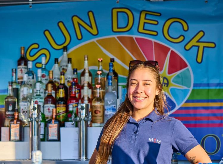 bartender girl smiling liquor bottles behind and Sun deck logo