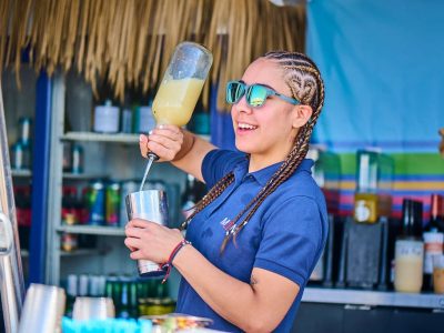 women bartender with braids sunglasses pouring a drink