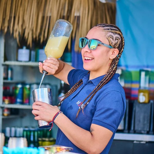 women bartender with braids sunglasses pouring a drink