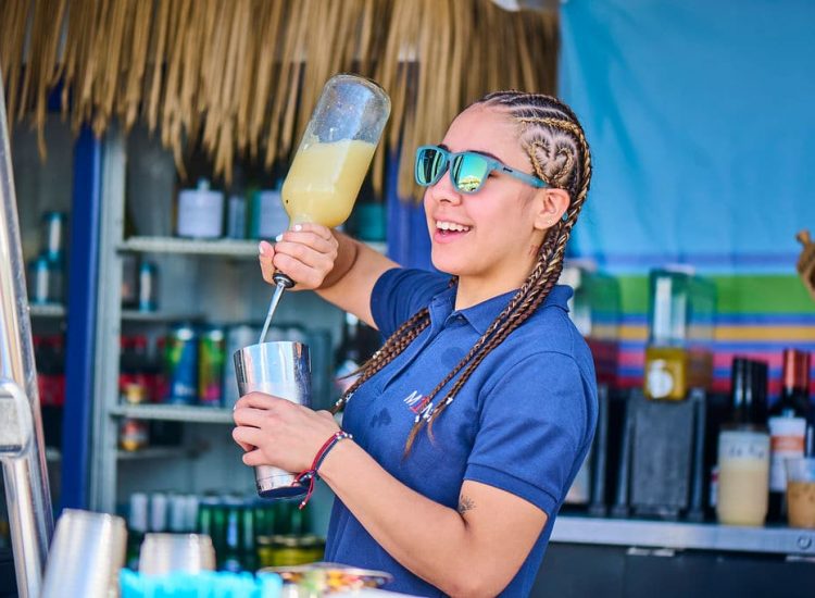 women bartender with braids sunglasses pouring a drink