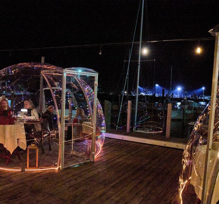 people at night dining in clear dome on the water