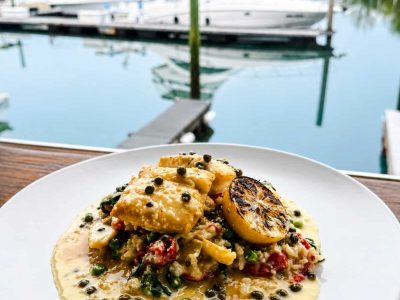 Halibut over risotto on a white plate with water and boats