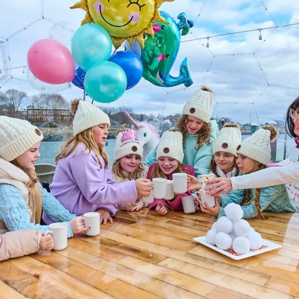 girls in pom hats with hot chocolate toasting with snow white