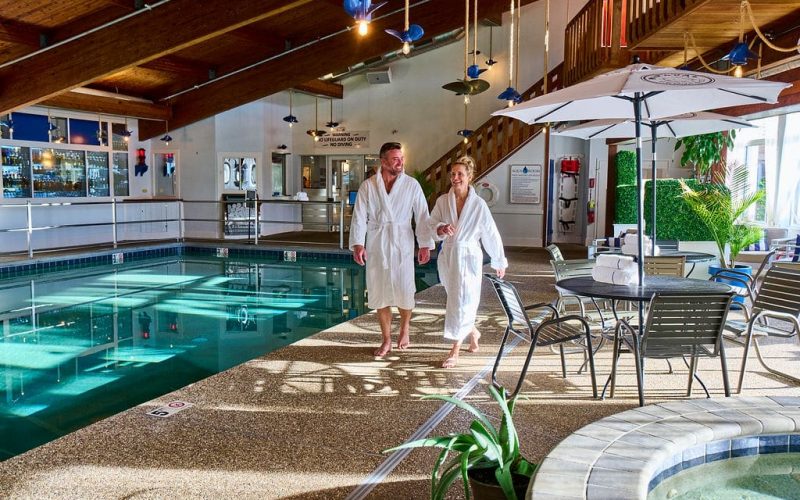a man women walking i robes next to an indoor pool