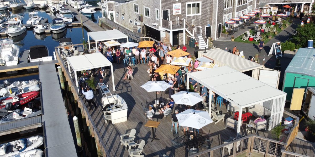Drone shot of deck with umbrella next to marina with boats