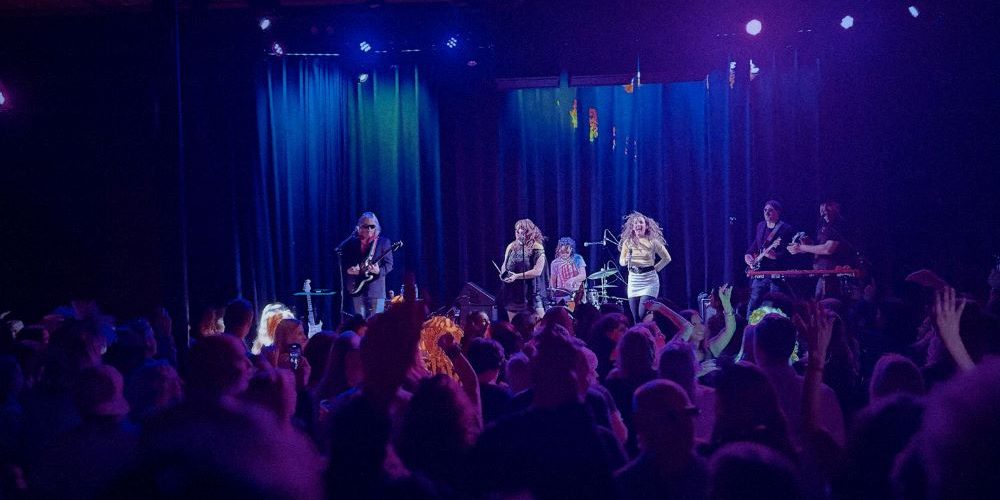 a live band on stage concert curtains and back of peoples heads