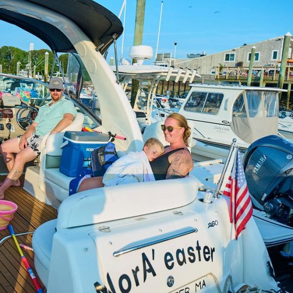 family sitting on a boat at a dock with sunglasses on