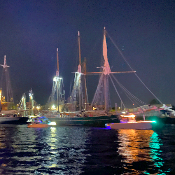 Schooner at night with boats parading by